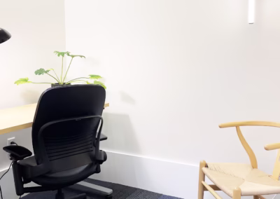 Solo annex office with sit-stand desk and glass door facing skylit atrium, available full-time or part-time now.